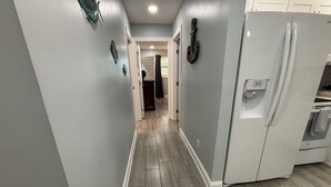 A narrow hallway with light gray walls and wooden flooring.