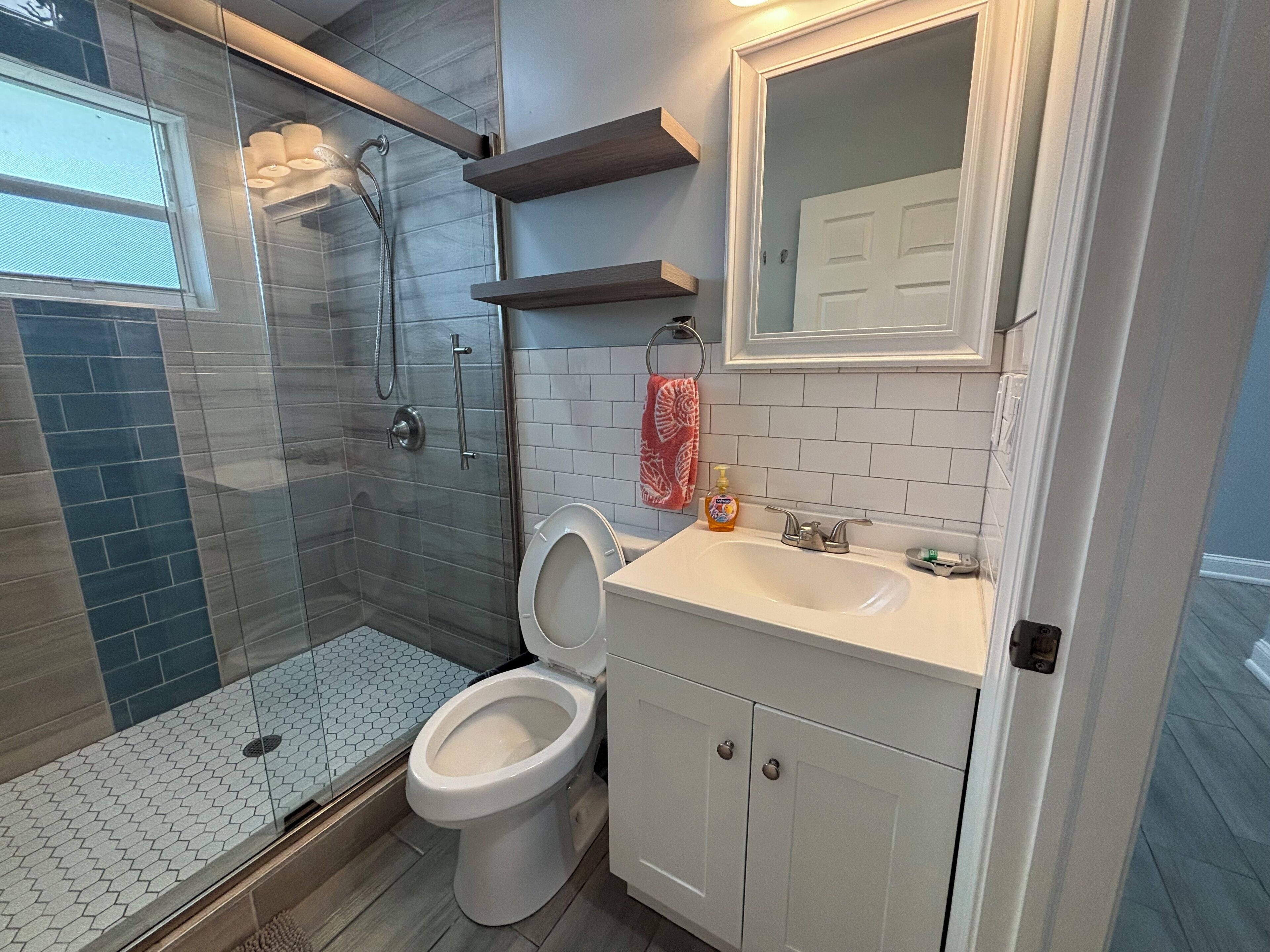 Une salle de bain moderne dotée d’une douche à parois de verre, de toilettes, d’un lavabo et d’un miroir.
