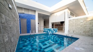 A swimming pool with a checkered pattern, surrounded by stone walls and a blue-tiled wall. - HOTEL SANTA MARTA TROPICAL (Santa Marta)