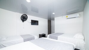 A hotel room with two beds, a ceiling fan, an air conditioning unit, and a small table with a television. - HOTEL SANTA MARTA TROPICAL (Santa Marta)