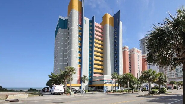Ein mehrstöckiges Hotel mit modernem Design, das geschwungene und gerade Linien kombiniert, und einen markanten Eingang mit Glasfassade.