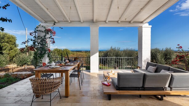 Un patio al aire libre con una mesa de madera, sillas y un sofá.