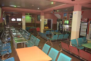 En restaurant med flere borde, stole, et fjernsyn og et køleskab.
