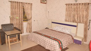 Ein Schlafzimmer mit Bett, Stuhl, Tisch und Vorhängen.