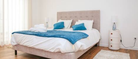Um quarto com uma cama, mesas de cabeceira, abajur e tapete.