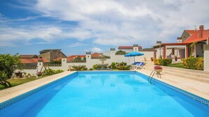 A swimming pool with a fountain, surrounded by a garden and a building with a red roof. - Pata da Gaivota Boutique House (Lourinha)