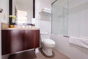 Ein modernes Badezimmer mit einem Holzausleger, einer Toilette, einer Duschkabine aus Glas und einem Handtuchhalter.