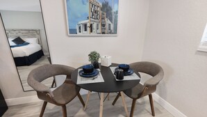 A dining area with a round table, two chairs, a small potted plant, and a framed picture on the wall. - Deluxe Room with Queen Bed and Kitchenette (Clearwater)