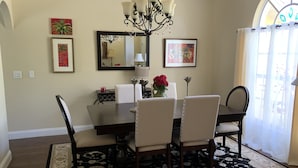 Un comedor con candelabro, obras de arte enmarcadas y un jarrón con flores.