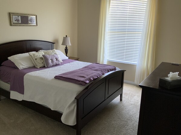 A neatly made bed with a dark headboard, a bedside table with a lamp, and a window with blinds. - Pool and heated spa, 3 bedroom, 2 baths, golf, beaches, safe community. (Apollo Beach)