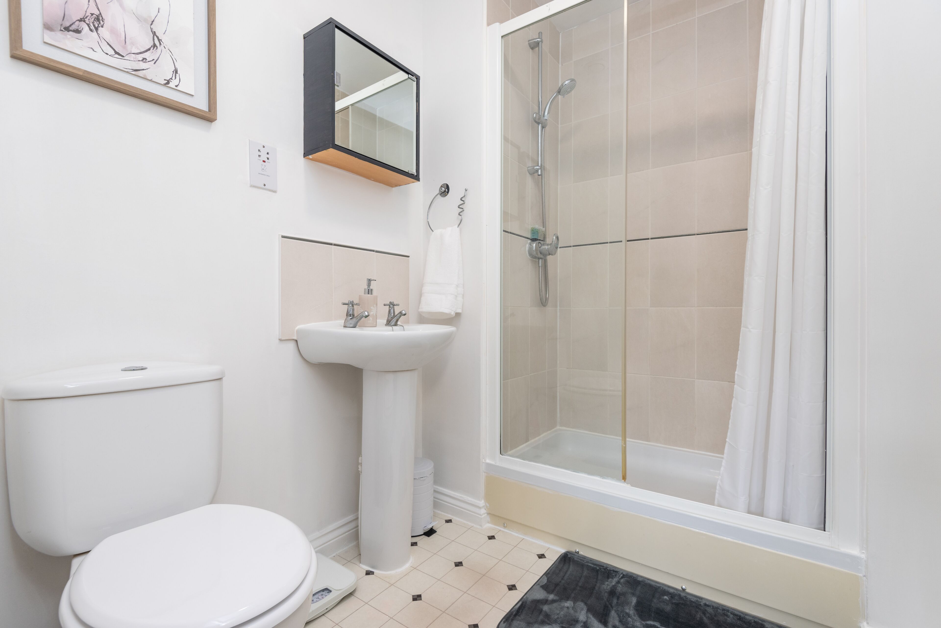 Un baño con inodoro, lavamanos y cabina de ducha de vidrio.