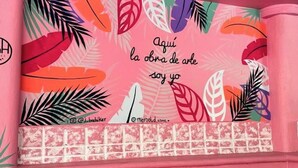 A colorful wall with a quote in Spanish, a patterned lower section, and a pink ball pit below.