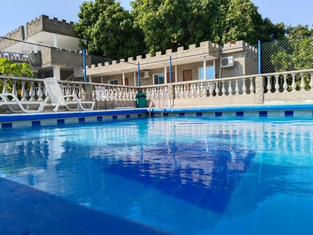 Una piscina con barandilla blanca, una escalera y un edificio de piedra con fachada de castillo al fondo.