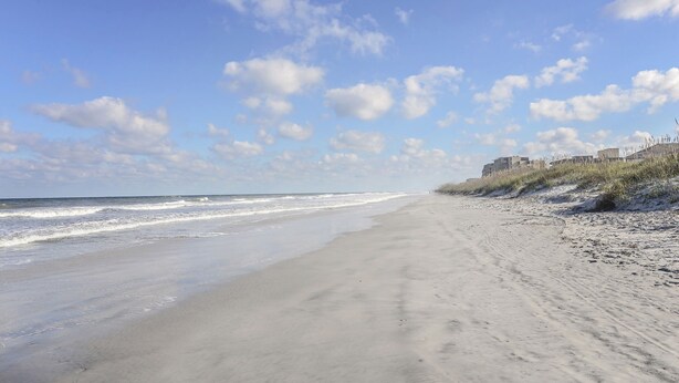 Ein Strand mit klarem Himmel und Wellen.