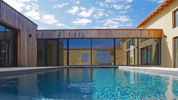 A modern house with a swimming pool, large glass doors, and a wooden exterior.