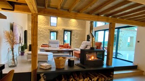 A modern living room with a stone wall, a fireplace, and a large window.