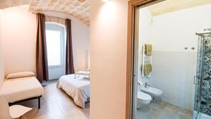 Une pièce comprenant un lit, une chaise, une fenêtre avec des rideaux, une salle de bain avec une douche et un sol carrelé.