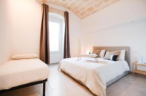 Une chambre à coucher avec un lit, une table de chevet, une fenêtre avec des rideaux et un plafond en briques.