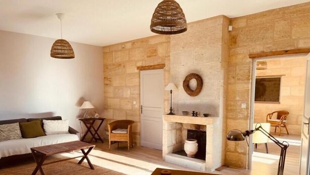 Una sala de estar acogedora con chimenea de piedra, un sofá, una mesa de centro de madera y sillones de mimbre.