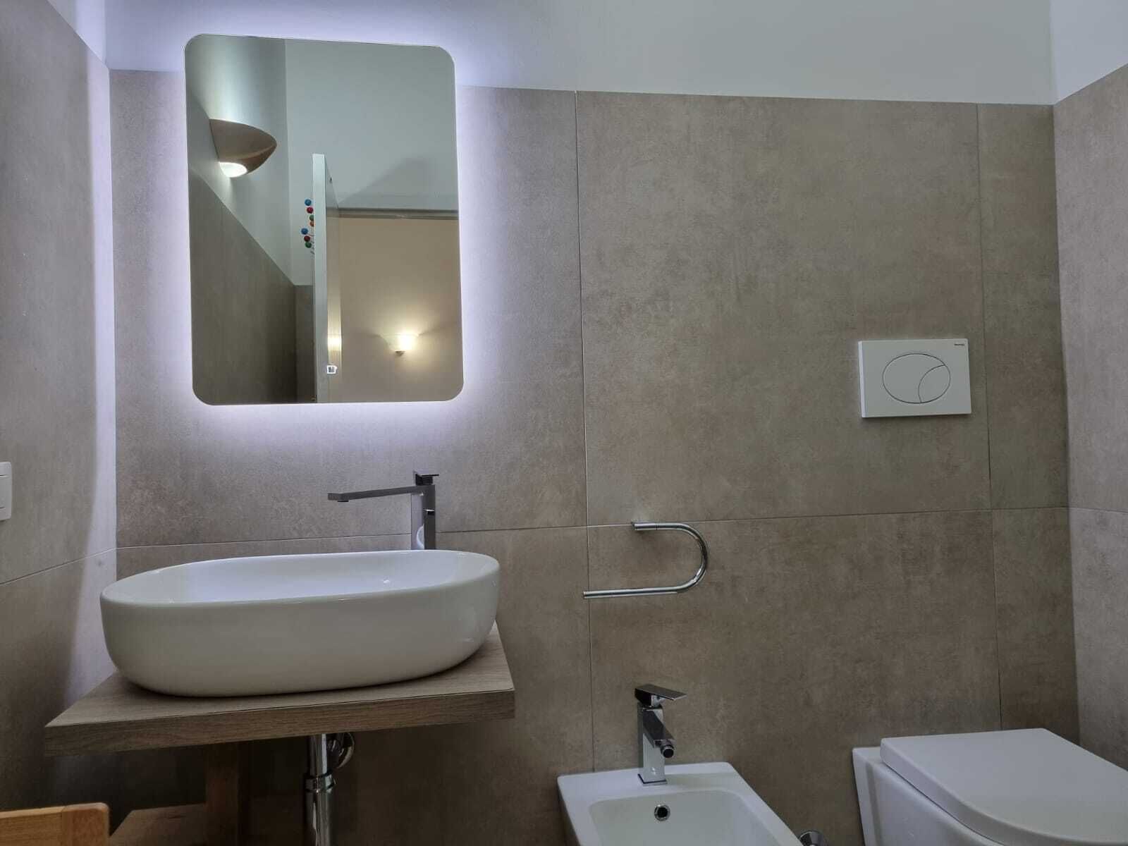 A modern bathroom with a large sink, a mirror, and a toilet.