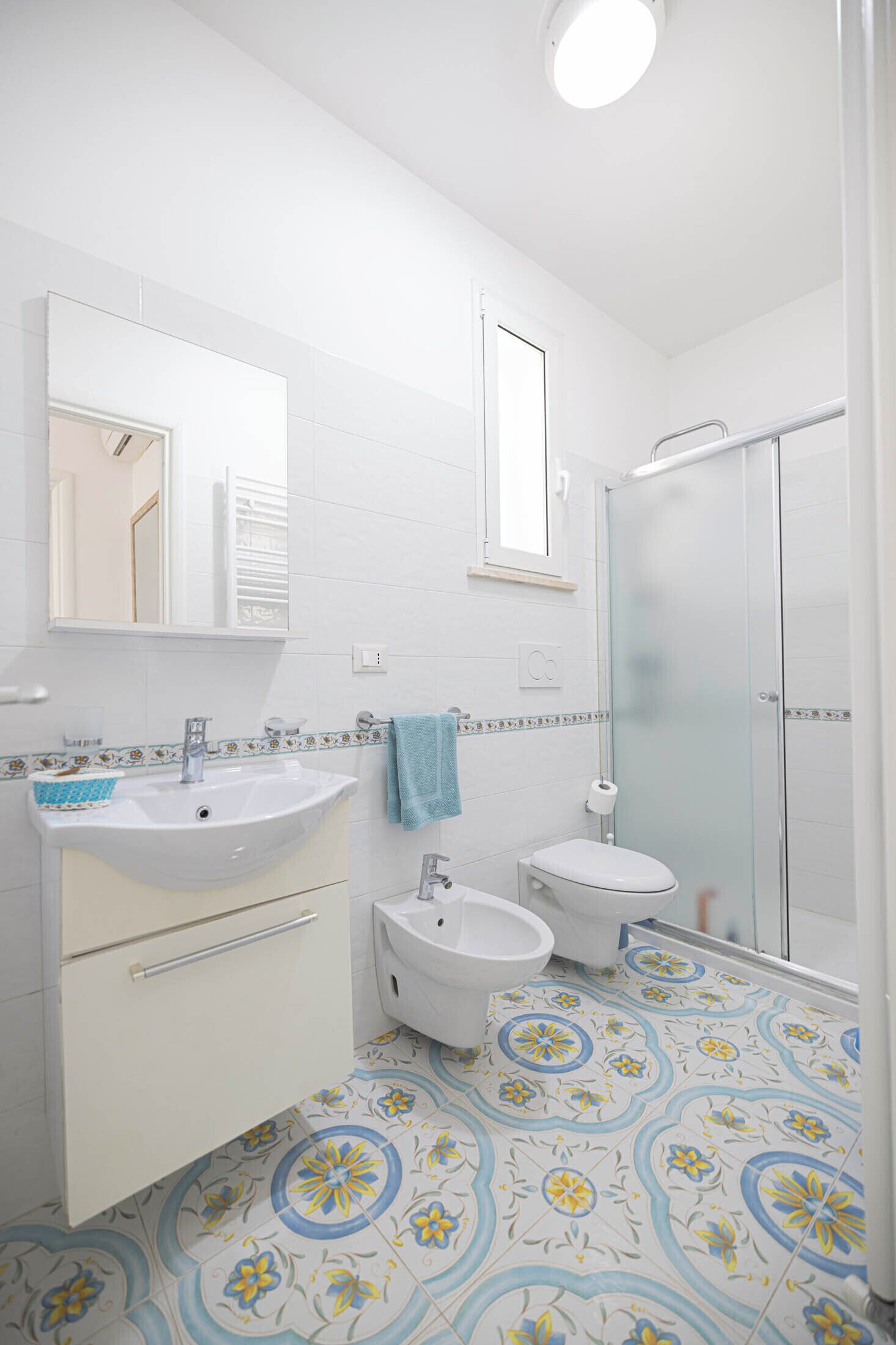 Et badeværelse med vask, toilet, bidet og en brusekabine i glas.
