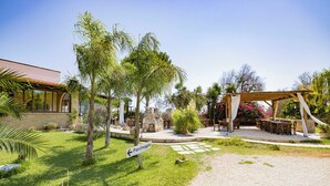 A courtyard with a pergola, outdoor seating, and a sign pointing to 'Parcheggio'.