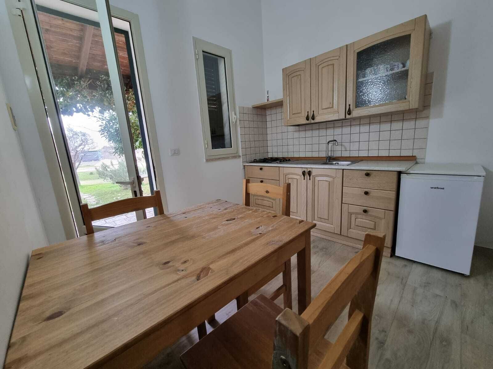 A kitchen with wooden cabinets, a white refrigerator, and a wooden dining table with chairs.