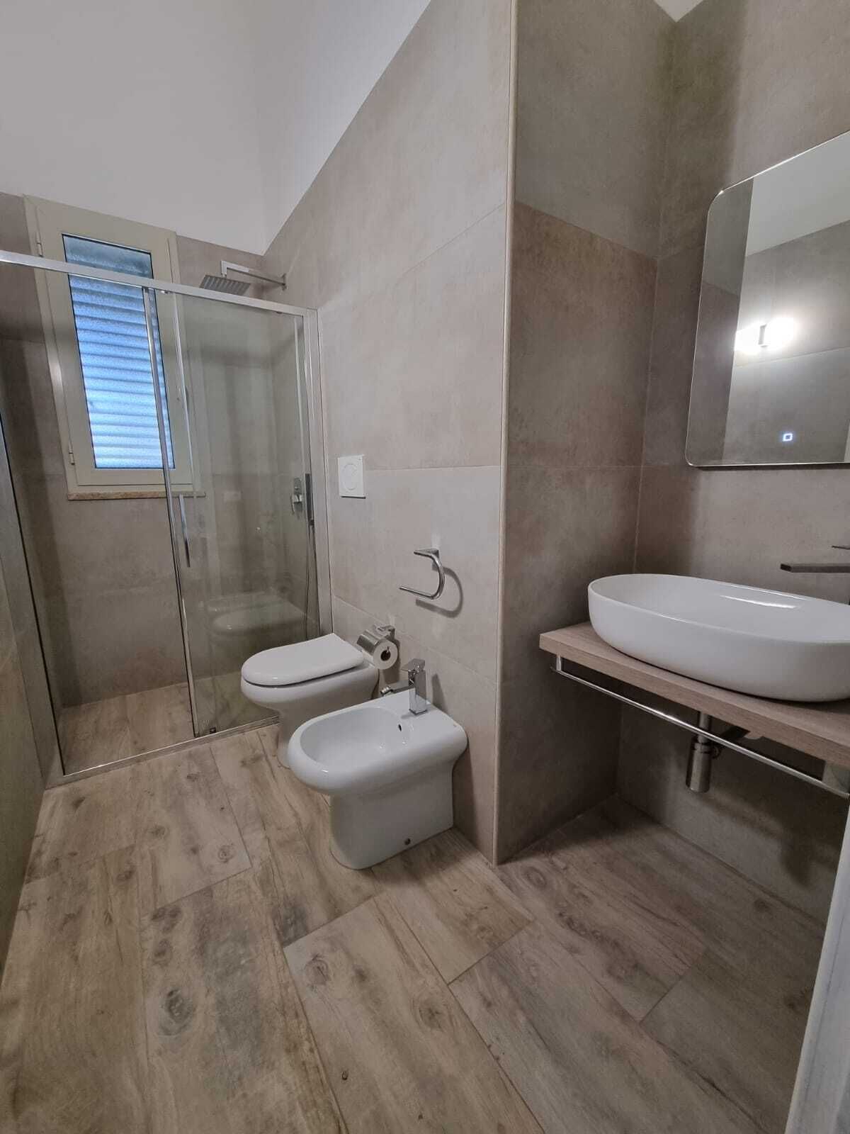 A modern bathroom with a shower, toilet, bidet, and sink.