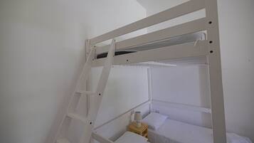 A bunk bed with a ladder, a small wooden nightstand with a lamp, and a white pillow.
