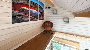 Ein Zimmer mit einem großen, felsen-inspirierten Gemälde, einer Holzbalkendecke und einem kleinen Sessel mit Kissen.