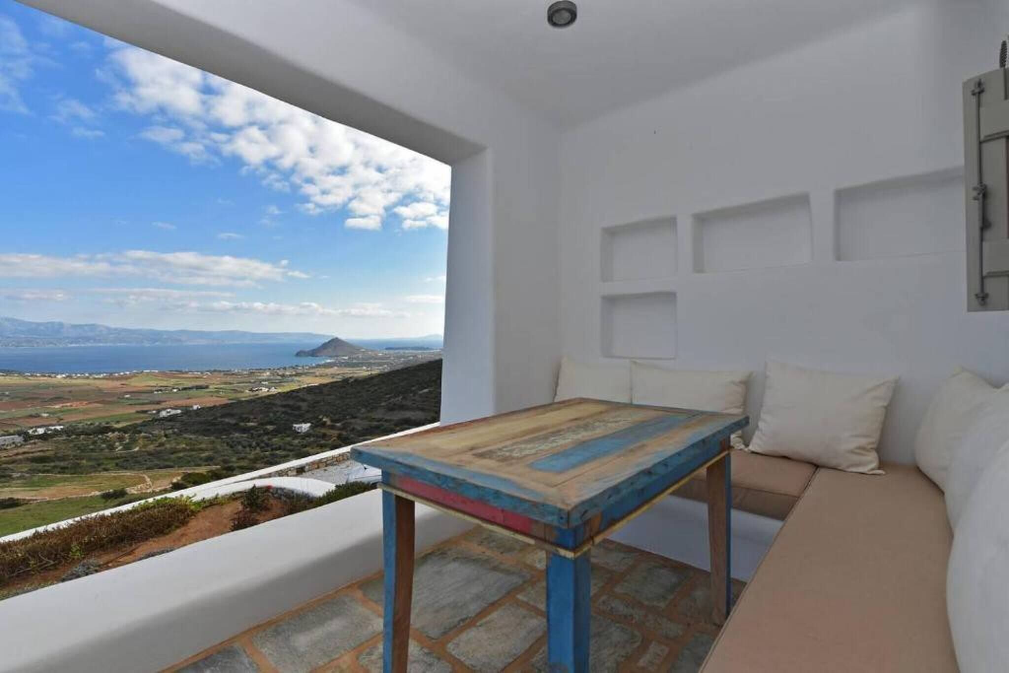 A balcony with a view of a coastal landscape, a wooden table, and a white sofa.