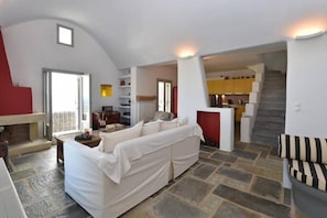 En modern inredning med ett stengolv, en vit soffa, en randig soffa och ett köksområde.
