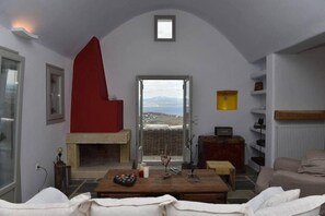 Un salon avec une cheminée, une vue à travers une porte et un mur d’accent de couleur rouge.