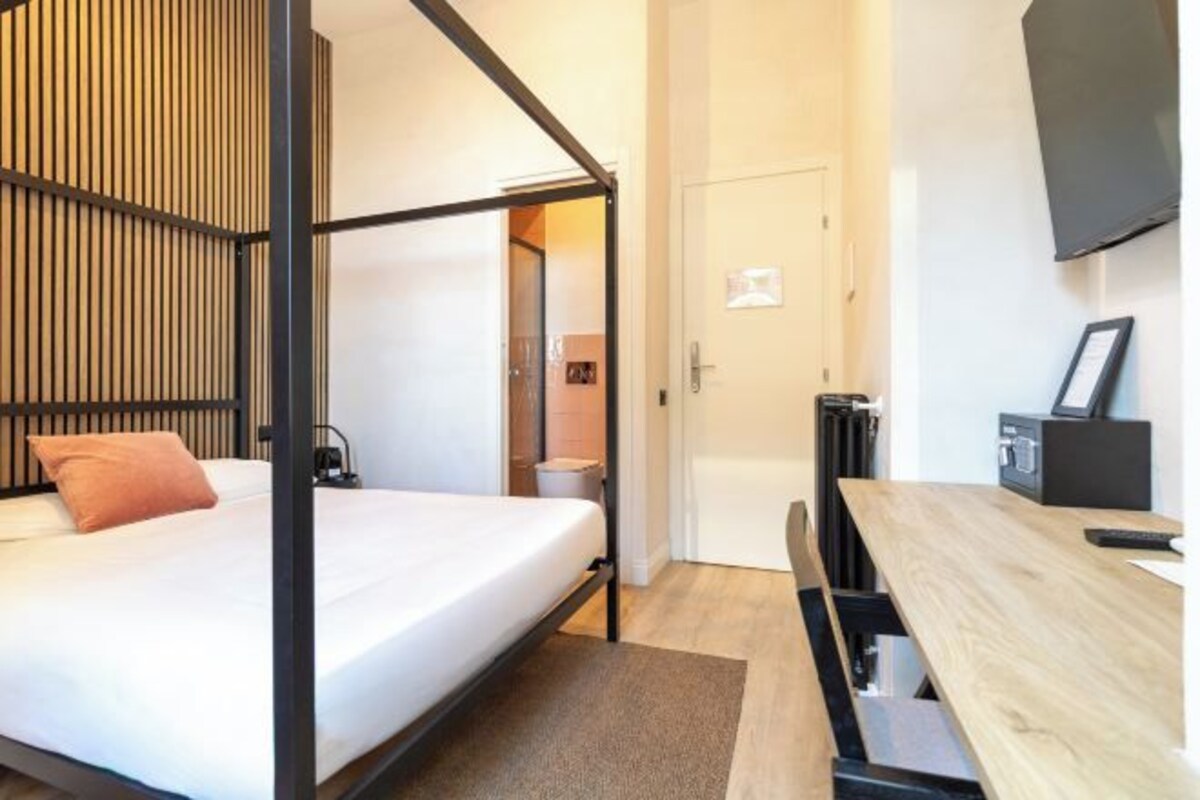 A modern room with a bunk bed, a desk, a chair, a radiator, and a television.
