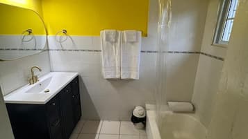 A bathroom with a white sink, a toilet, and a bathtub. There are two towels hanging on hooks.