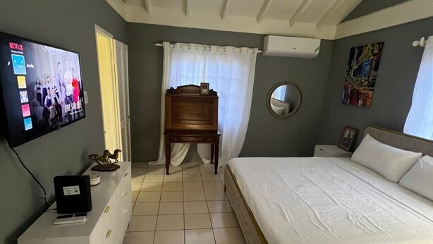 A hotel room with a bed, a desk, a television, and a ceiling fan. - The Polo Club at Racquet Club (Montego Bay)