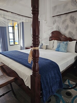 Una cama con dosel, un cabecero de madera y una colcha azul con textura.