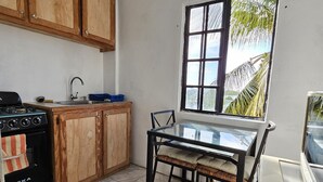 Una cocina con gabinetes de madera, estufa a gas, lavamanos y una mesa de comedor con sillas.