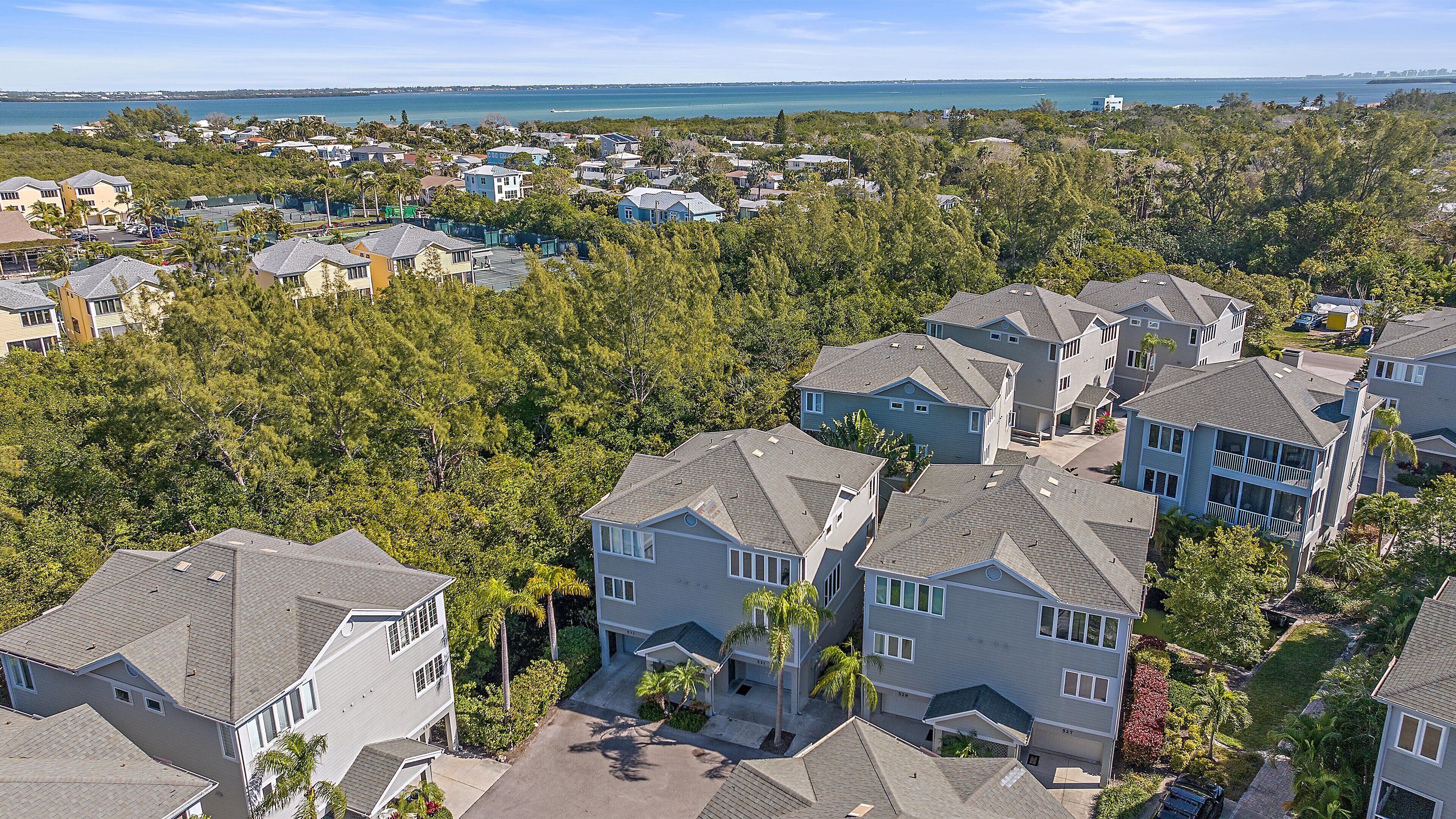 Un quartier résidentiel avec des maisons, une vue dégagée sur l’océan et une route menant à la plage.