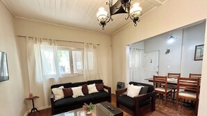 A living room with a sofa, coffee table, and dining area with chairs.
