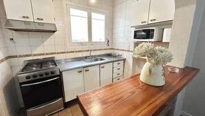 A kitchen with white cabinets, a stainless steel stove, a microwave, and a wooden countertop.