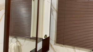 A bathroom with a mirror, a towel rack, and a marble wall. - Pousada Perola da Praia (Penha)