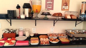 A breakfast buffet with various food items, a coffee machine, and a juice dispenser. - Pousada Perola da Praia (Penha)