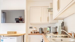A modern kitchen with white cabinets, a microwave, a toaster, and a sink.