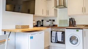 A compact kitchen with a built-in dishwasher, a microwave, and a washing machine.