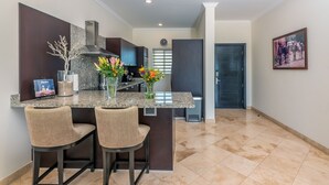 A modern kitchen with granite countertops, two bar stools, and a central island.