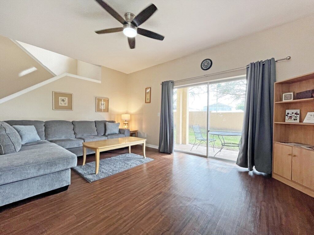 A modern living room with a grey sofa, wooden coffee table, and a ceiling fan.
