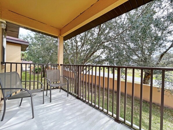 A covered outdoor area with a metal railing, two chairs, and a bench. - Updated resort home, south facing patio and balcony! (Davenport)