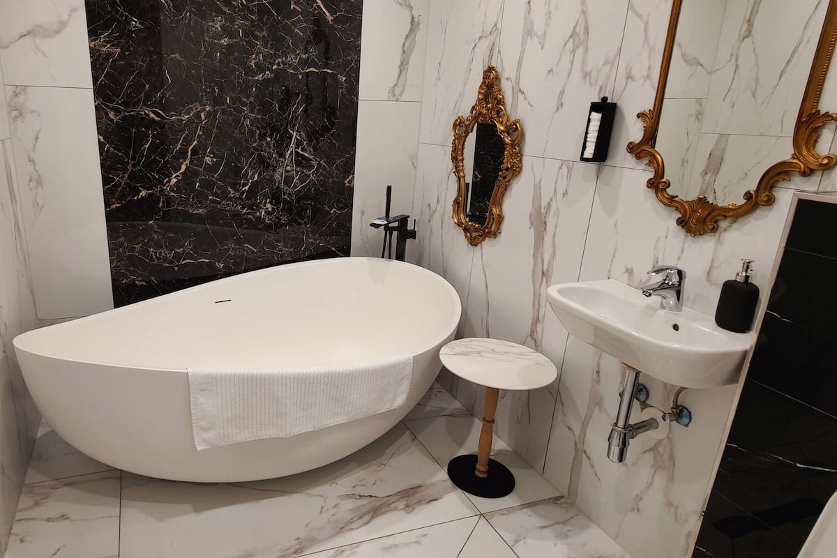 A modern bathroom with a freestanding bathtub, a small round sink, and a vanity with a mirror.