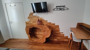 Une pièce avec un mur décoratif en bois, un téléviseur fixé au mur et un porte-manteau.